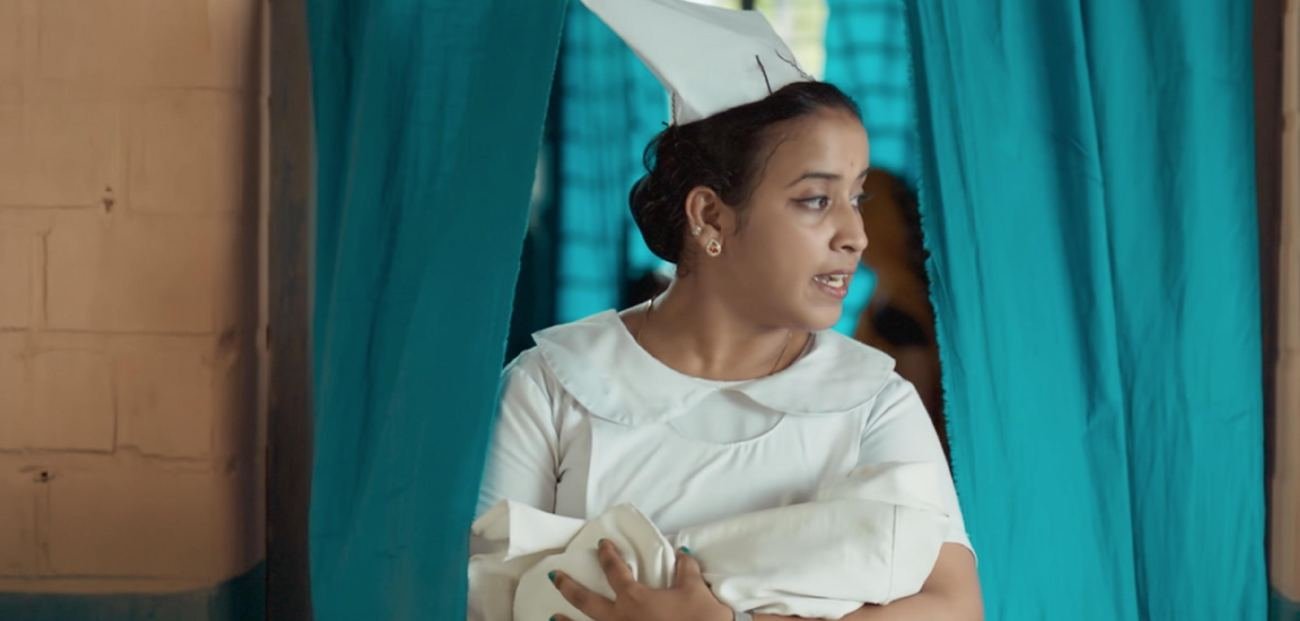 A nurse in a white uniform holds a newborn, still from the Smile Train film